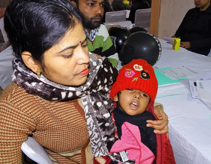 A mother holding her child at a doctor's table during the camp
